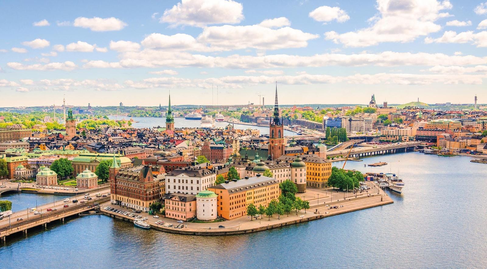 Blick auf Stockholms Altstadt mit bunten Gebäuden und Wasser bei blauem Himmel.