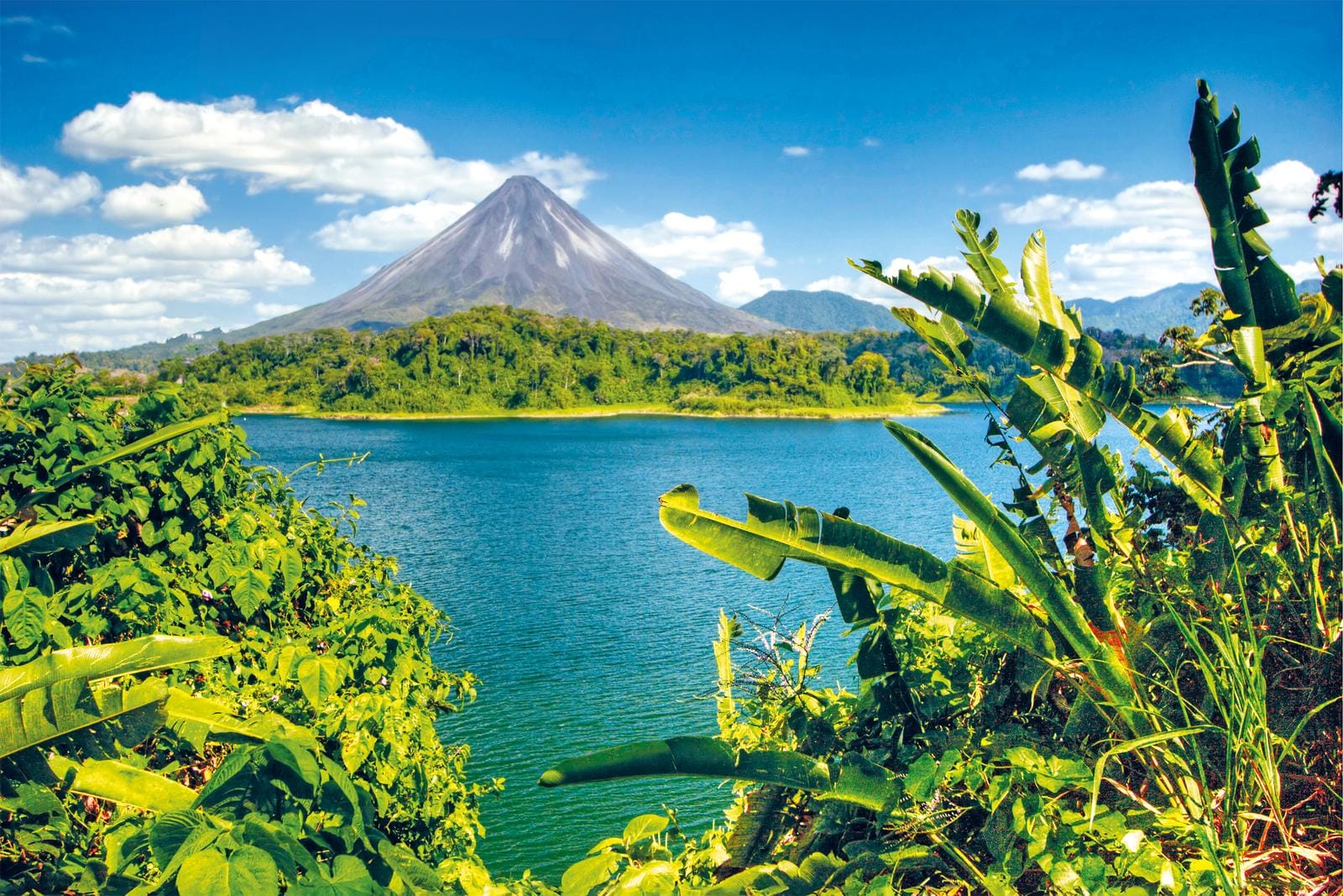 Tropischer See mit Vulkan Arenal in Costa Rica, umgeben von üppigem Grün.
