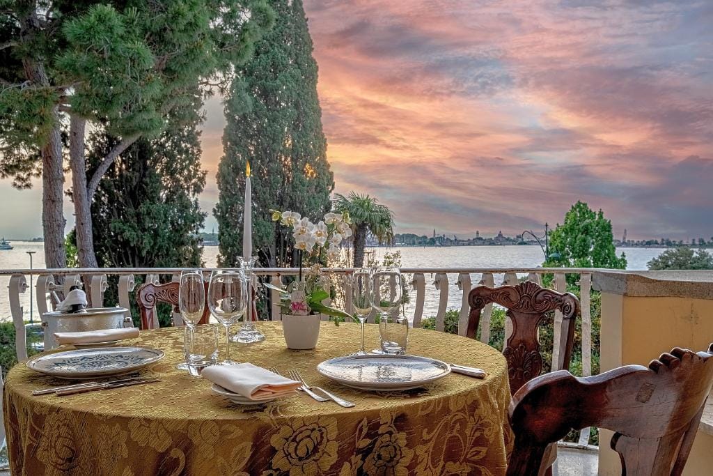 Elegantes Abendessen auf Terrasse mit Seeblick bei atmosphärischem Sonnenuntergang.