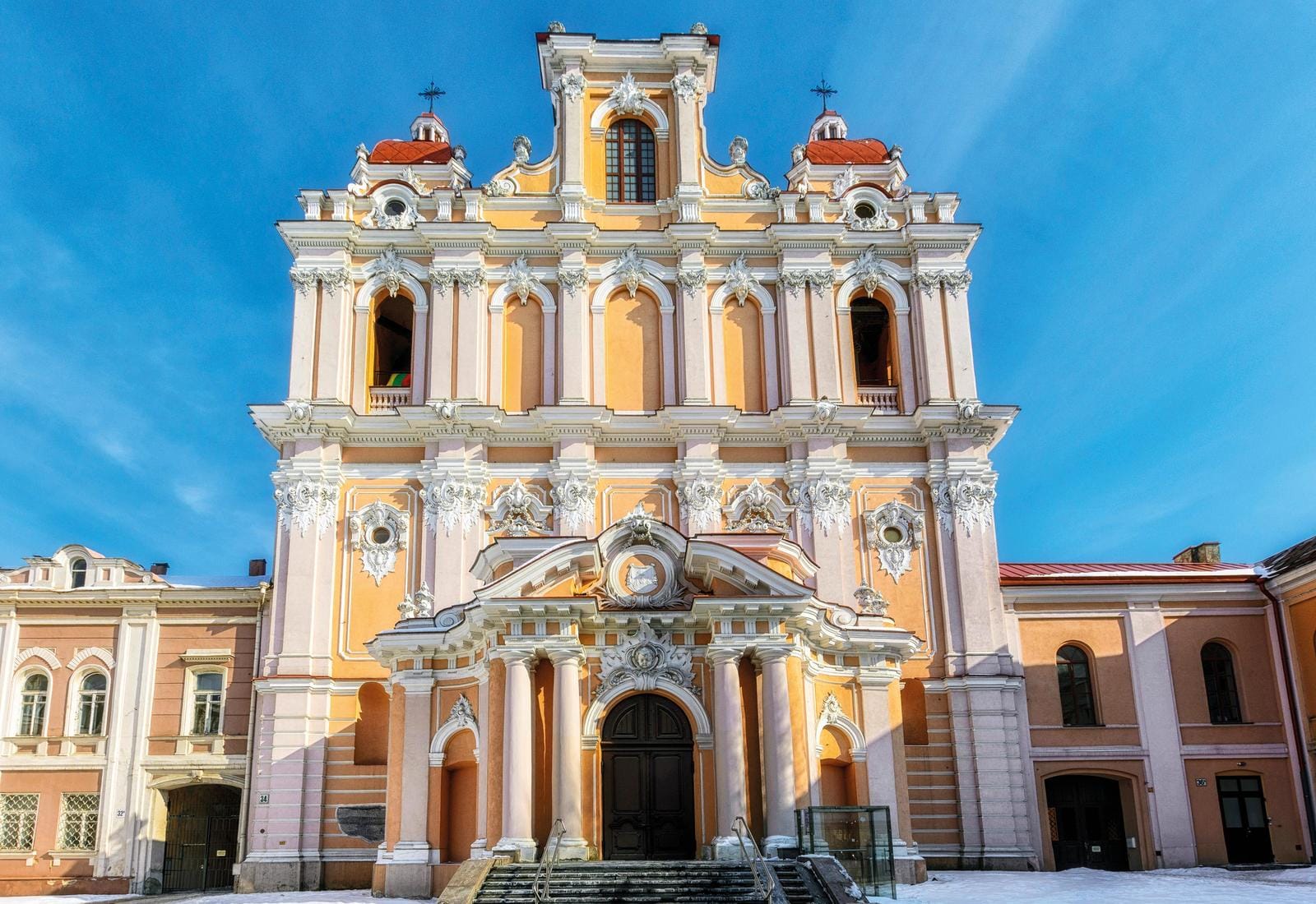 Barockkirche in Vilnius, Litauen mit prunkvoller Fassade vor blauem Himmel.