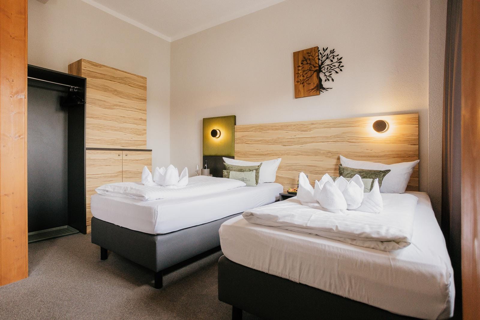 Modernes Hotelzimmer mit zwei Einzelbetten, Holzdekor, Kunstwerk und sanfter Beleuchtung.