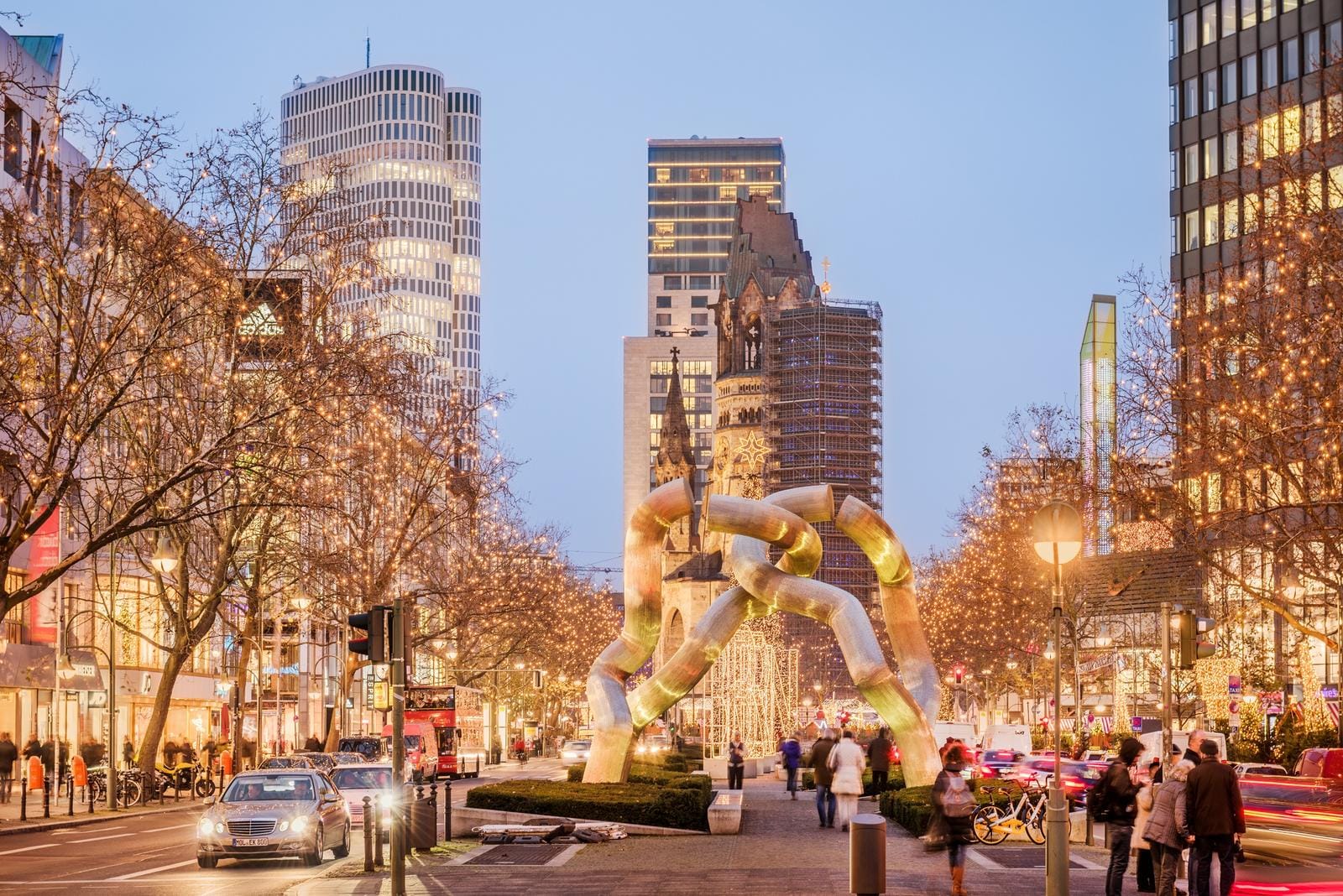 Beleuchtete StraĂe in Berlin mit moderner Skulptur und historischen GebĂ€uden.