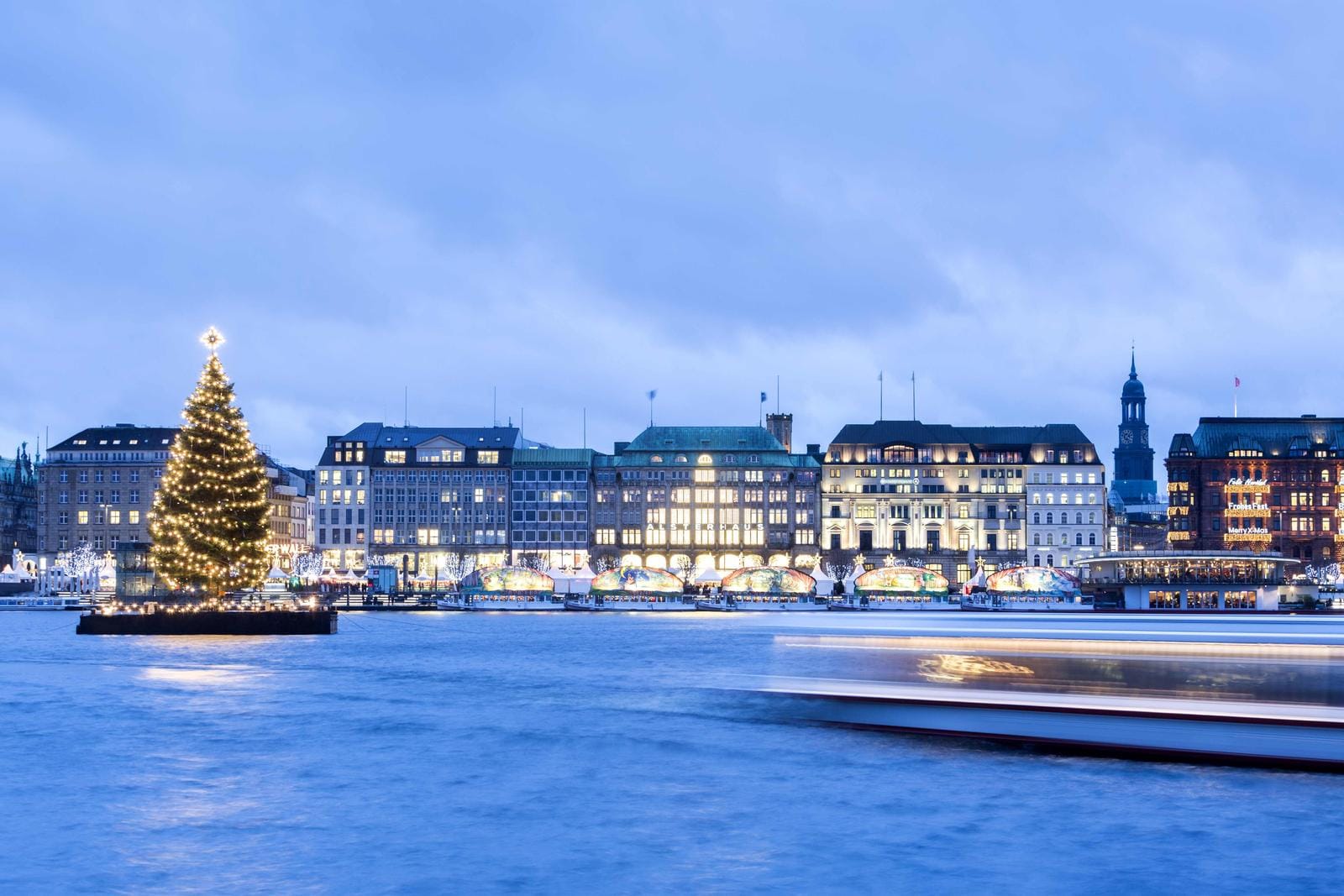 Weihnachtsbaum am Wasser, beleuchtete Gebäude, winterliche Stimmung, Hamburg, Deutschland.