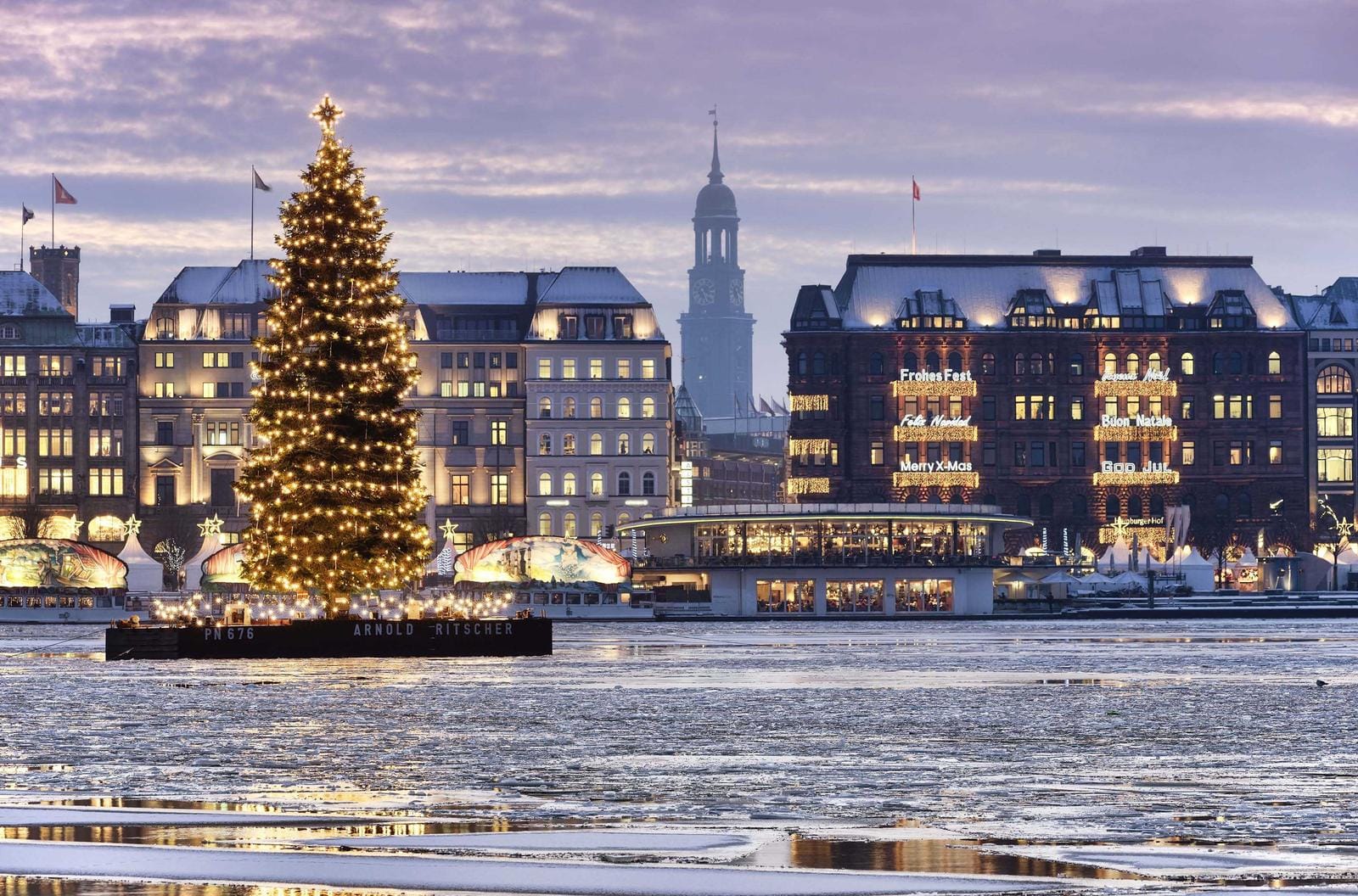 Weihnachtsbaum vor beleuchteter Kulisse in Hamburg, mit Alster und historische Gebäude.