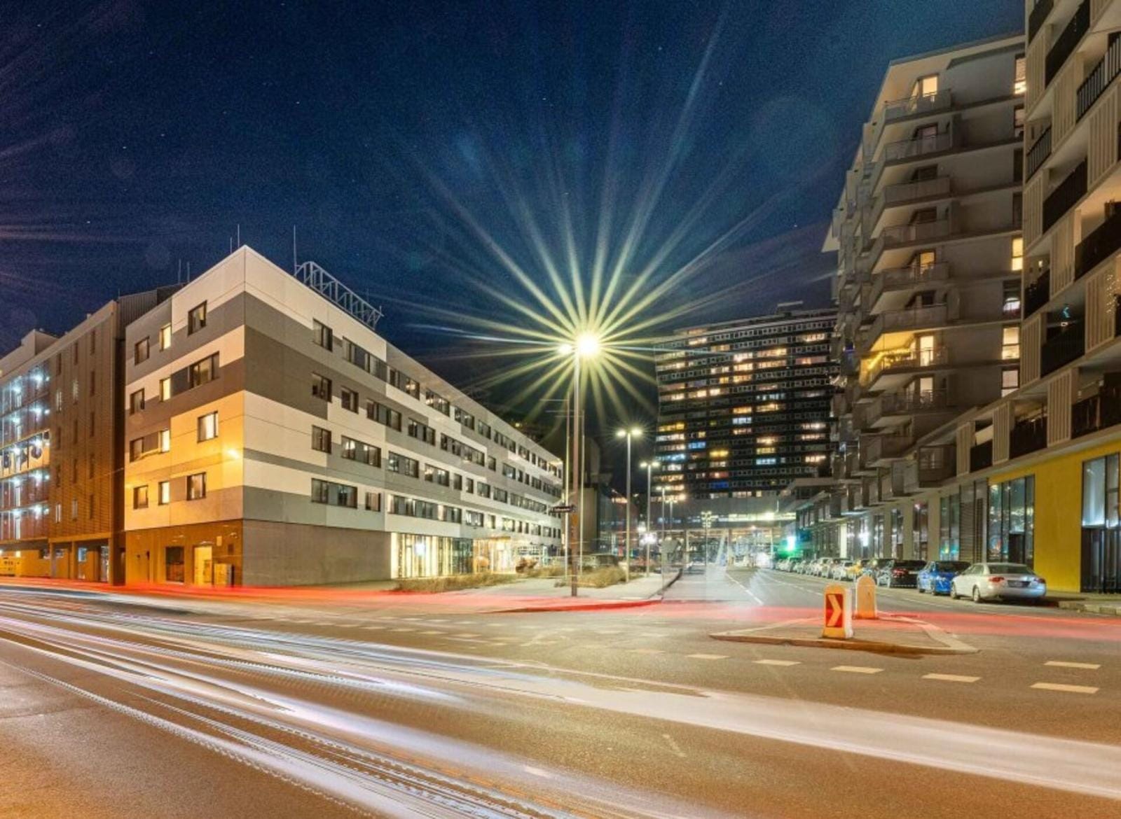 Moderne Stadtansicht bei Nacht mit beleuchteten Gebäuden und Lichtspuren.