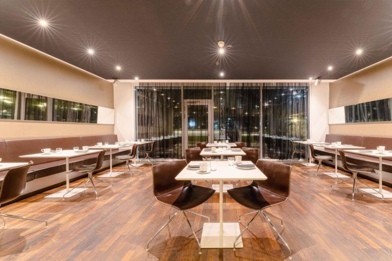 Modernes Restaurant mit Holzboden, eleganten braunen Stühlen und minimalistischer Einrichtung.