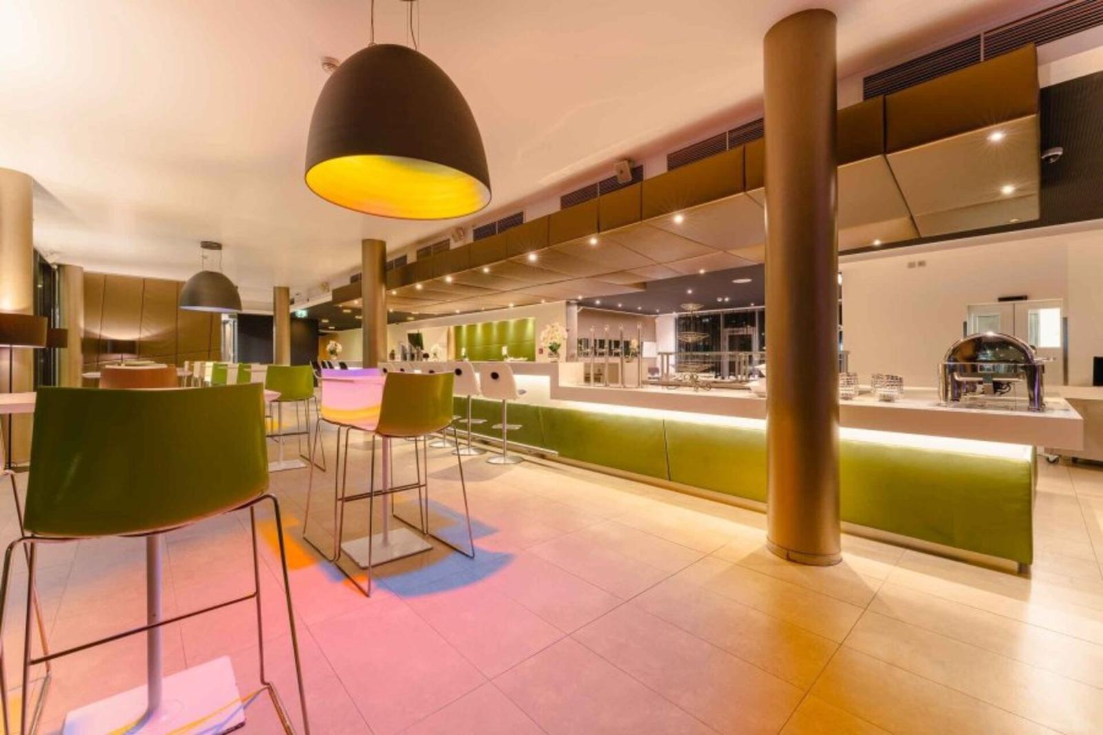 Moderne Hotel-Lobby mit grünen und weißen Stühlen, stimmungsvoller Beleuchtung.