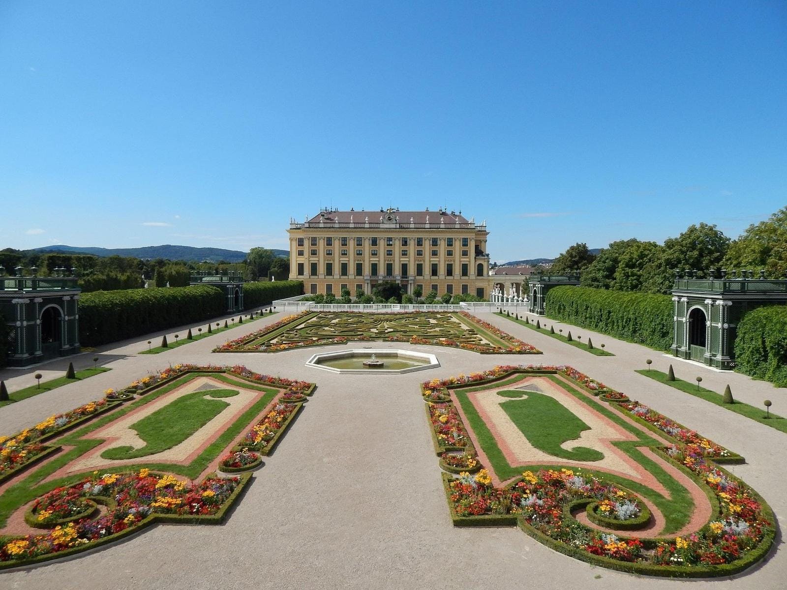 Schloss Schönbrunn in Wien, barocker Garten, klare Himmel, farbenfrohe Blumenbeete.
