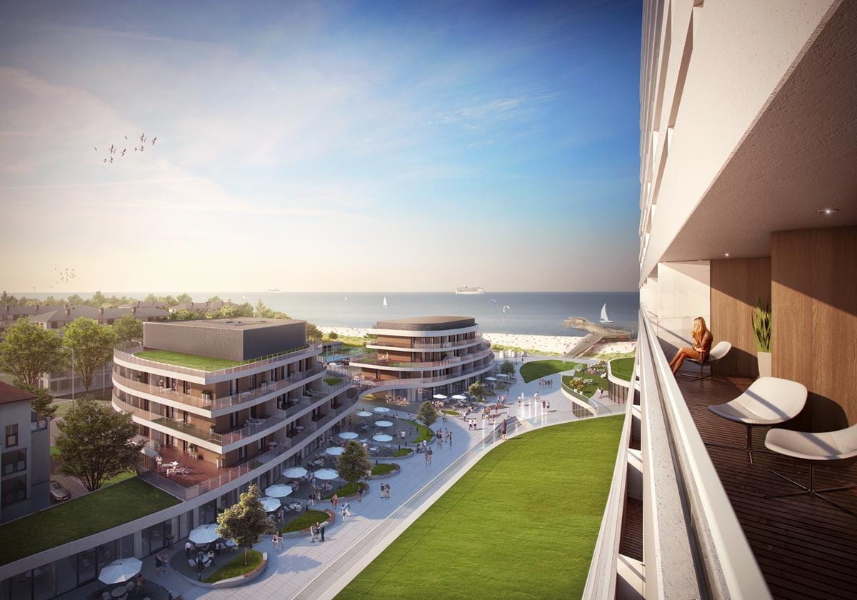 Moderne Hotelanlage am Strand mit runden Gebäuden, Terrasse, Meerblick und grünem Rasen.