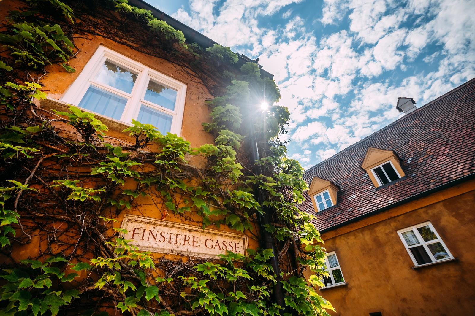 Gelbes Fachwerkhaus mit Efeu bewachsen, blauer Himmel, deutsches Dorfambiente.