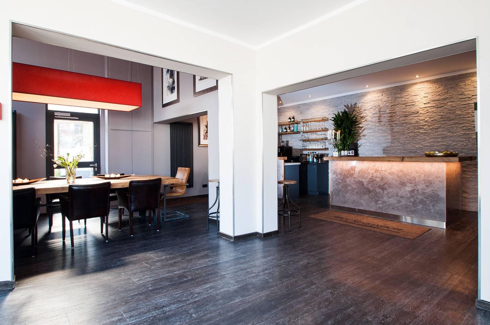 Modernes Hotel-Restaurant mit elegantem Holztisch, roter Lampe und stilvollem Tresen.