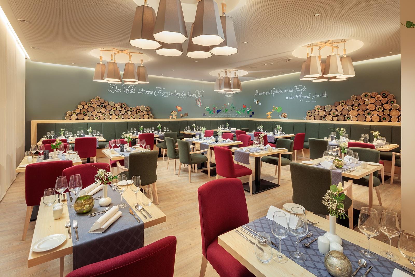 Elegantes Hotelrestaurant mit roten und grĂĽnen StĂĽhlen, dekorativem Holzwand-Design.