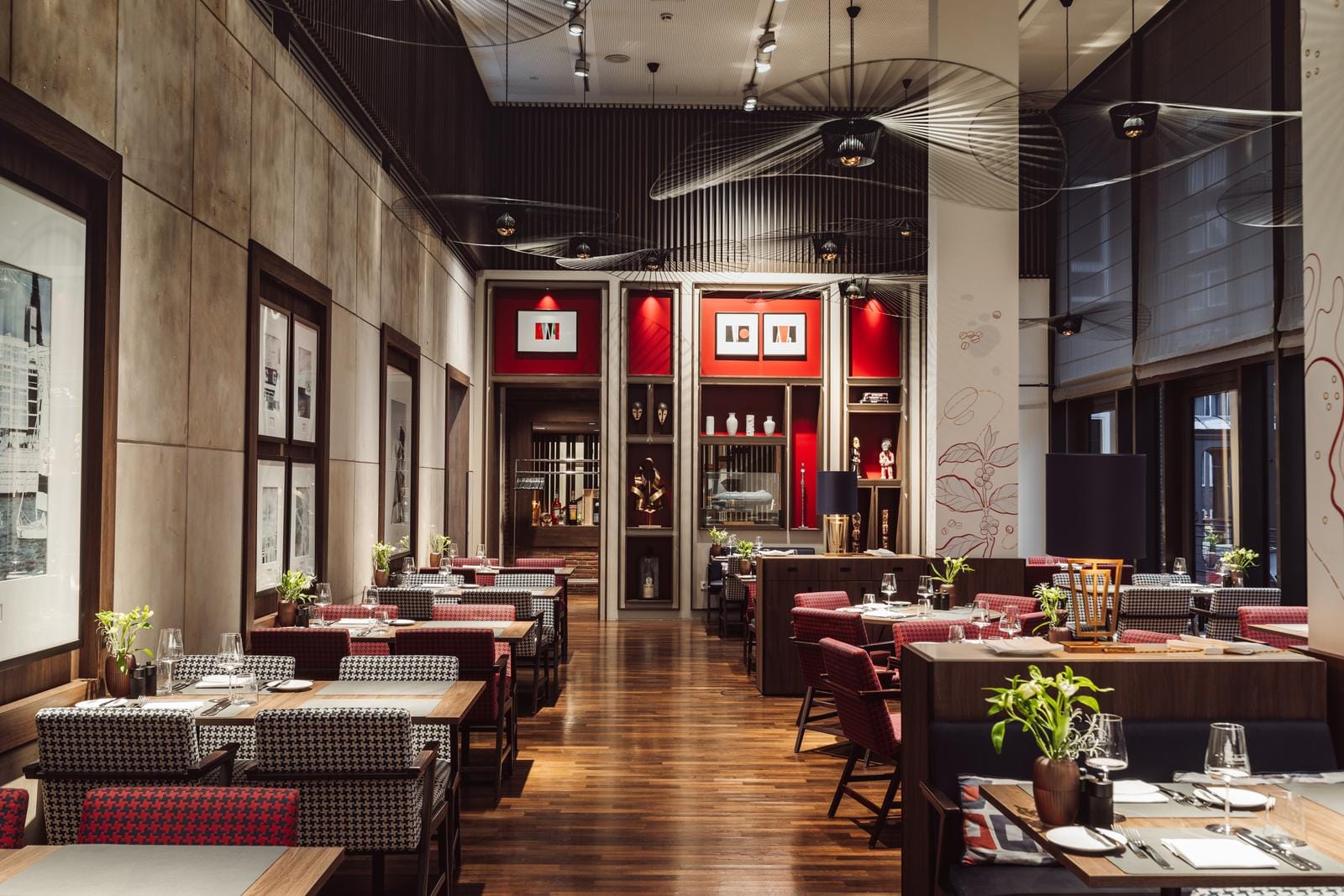 Elegantes Hotelrestaurant mit Holzboden, roten Akzenten und moderner Kunst an den Wänden.
