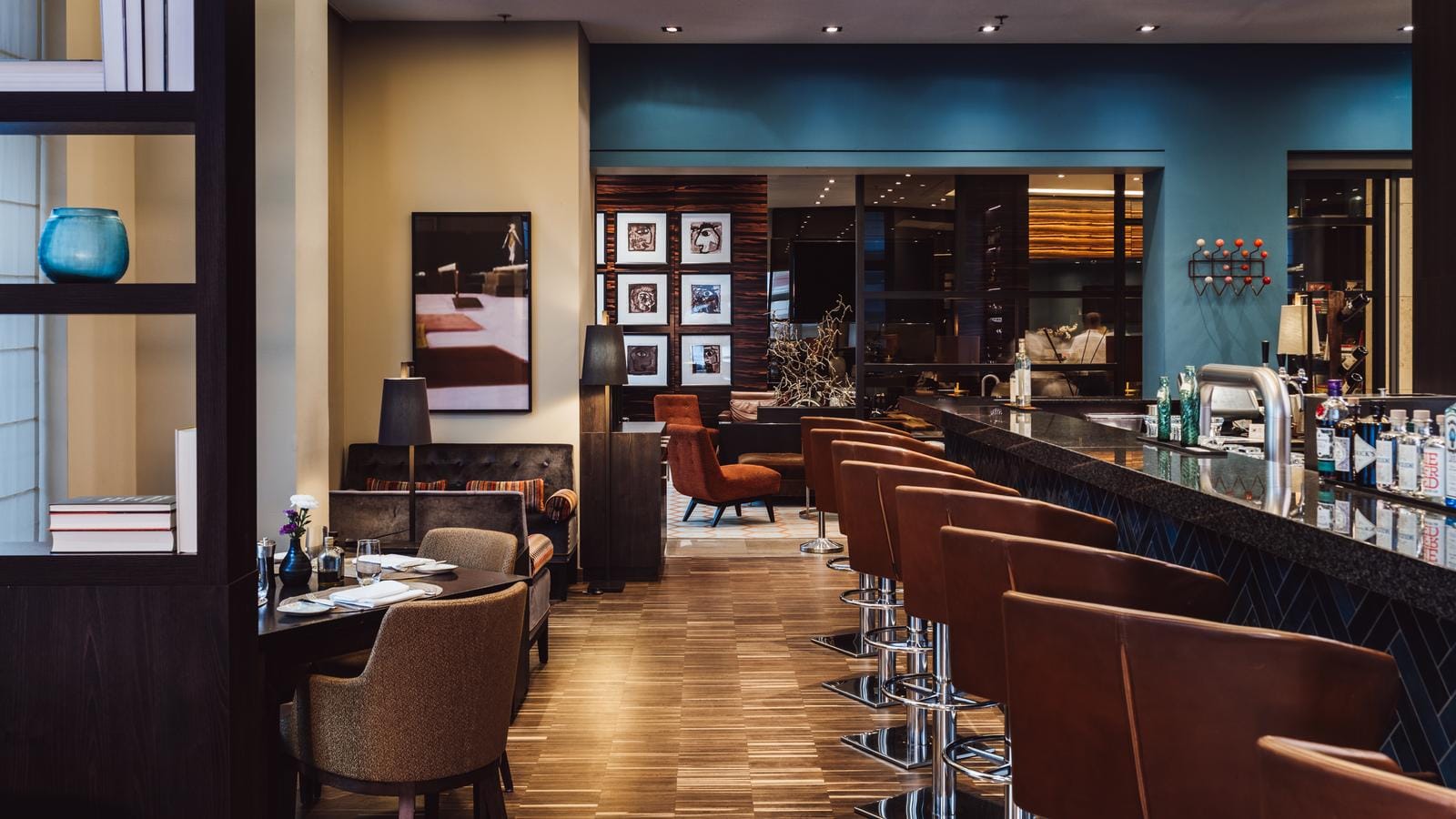 Elegante Hotelbar mit braunen Ledersesseln, blauer Wand und moderner, gemütlicher Atmosphäre.