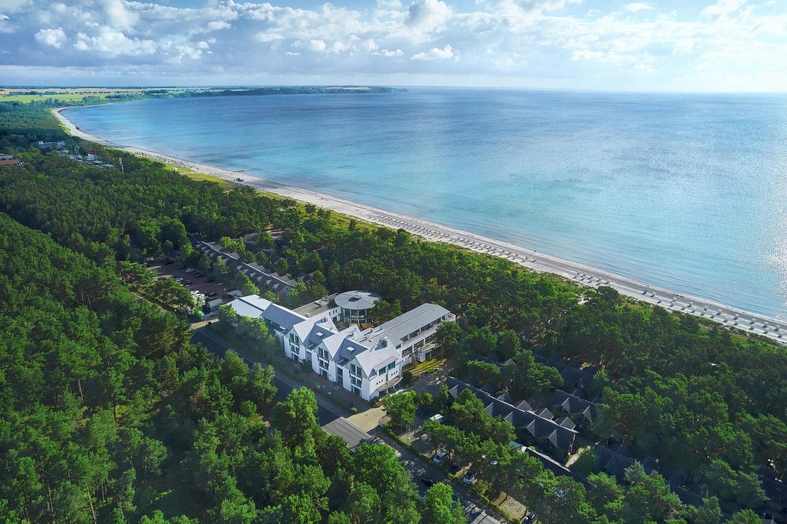 Hotel an der Ostseeküste mit direktem Strandzugang, umgeben von grünen Wäldern.