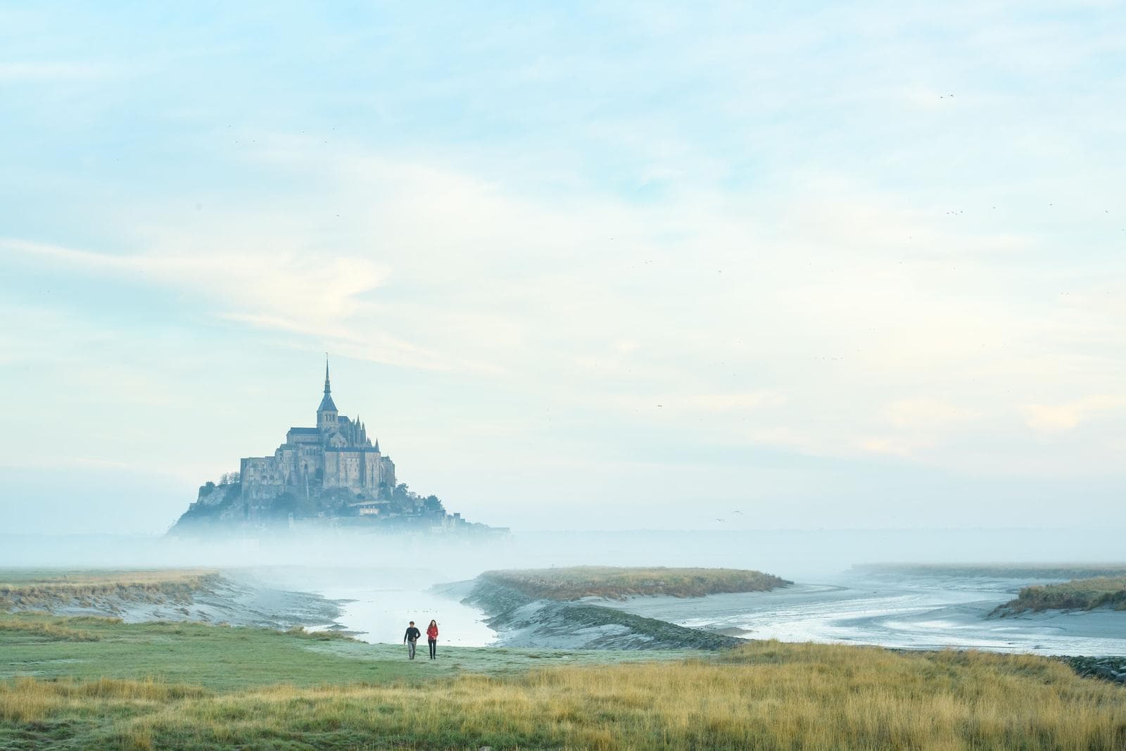 Mont-Saint-Michel in Frankreich, mystisch im Nebel, Küstenlandschaft bei Sonnenuntergang.