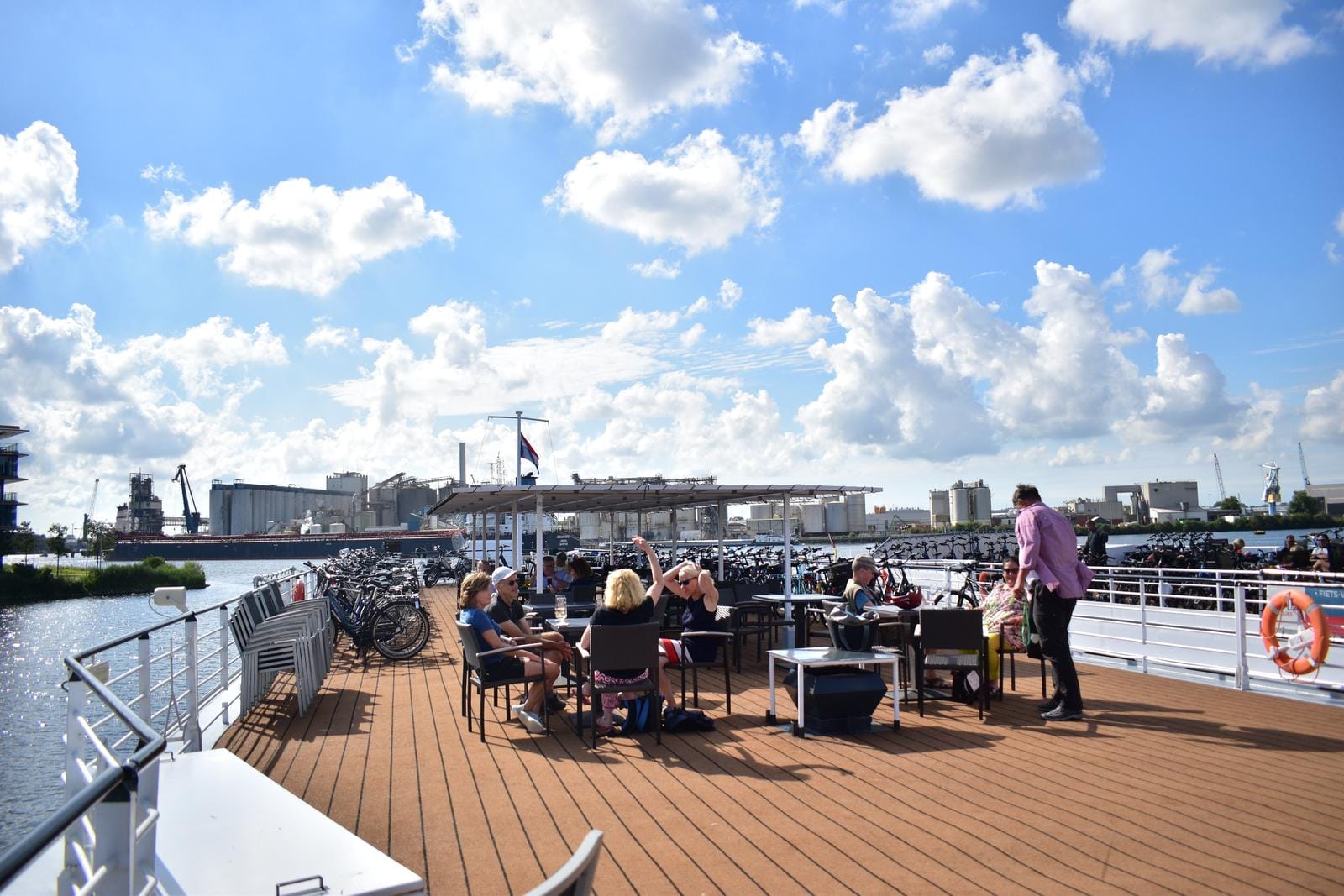 Sonniges Deck eines Flusskreuzfahrtschiffs, FahrrÀder, Hafen im Hintergrund, blauer Himmel.
