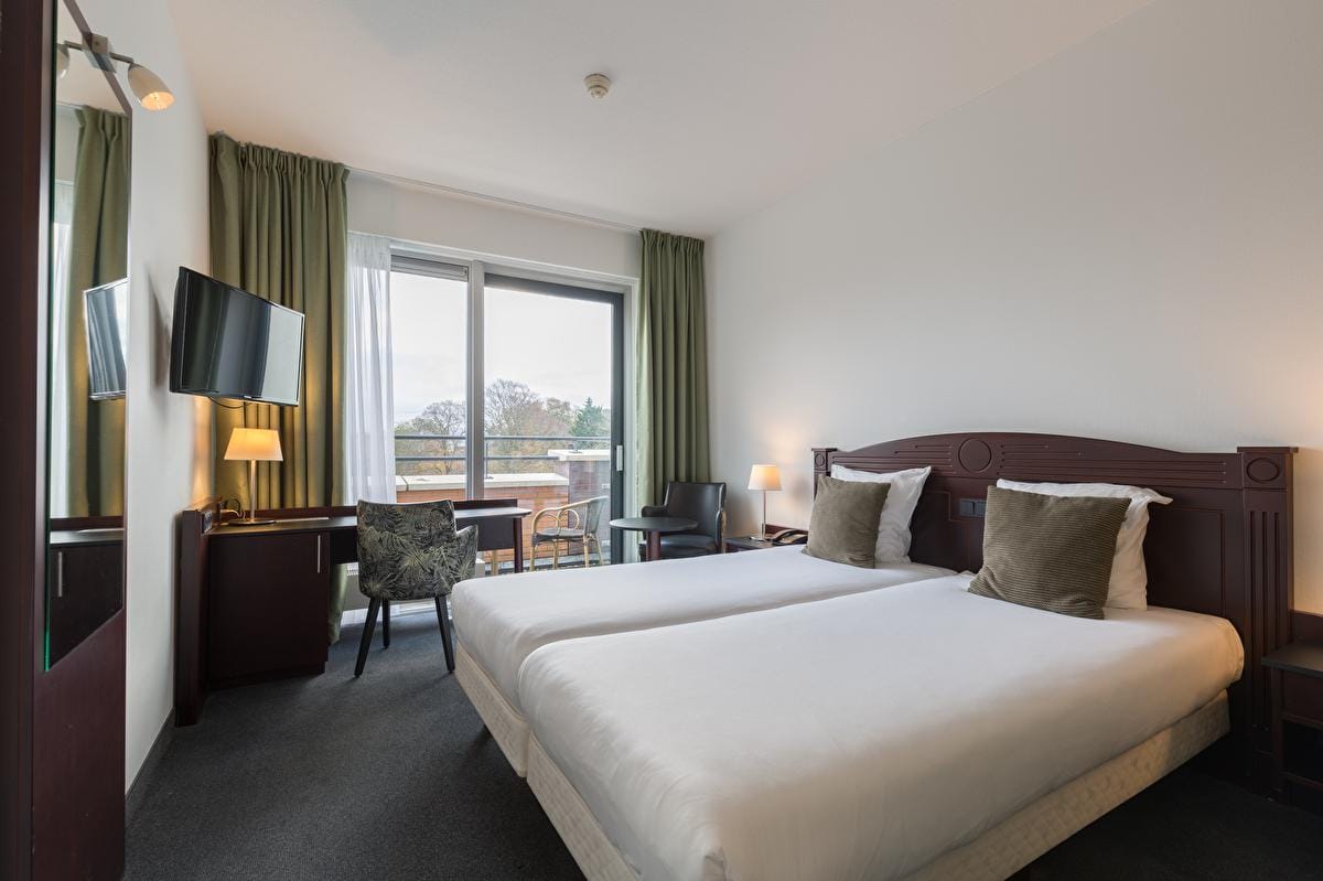 Modernes Hotelzimmer mit zwei Einzelbetten, grünen Vorhängen, Balkon und Flachbild-TV.