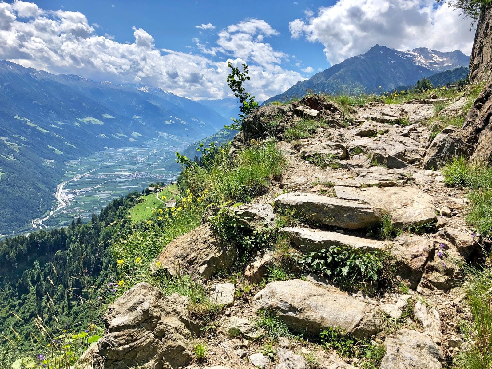 Steiniger Wanderweg in den Alpen, Berge und Tal im sonnigen Südtirol, Italien.