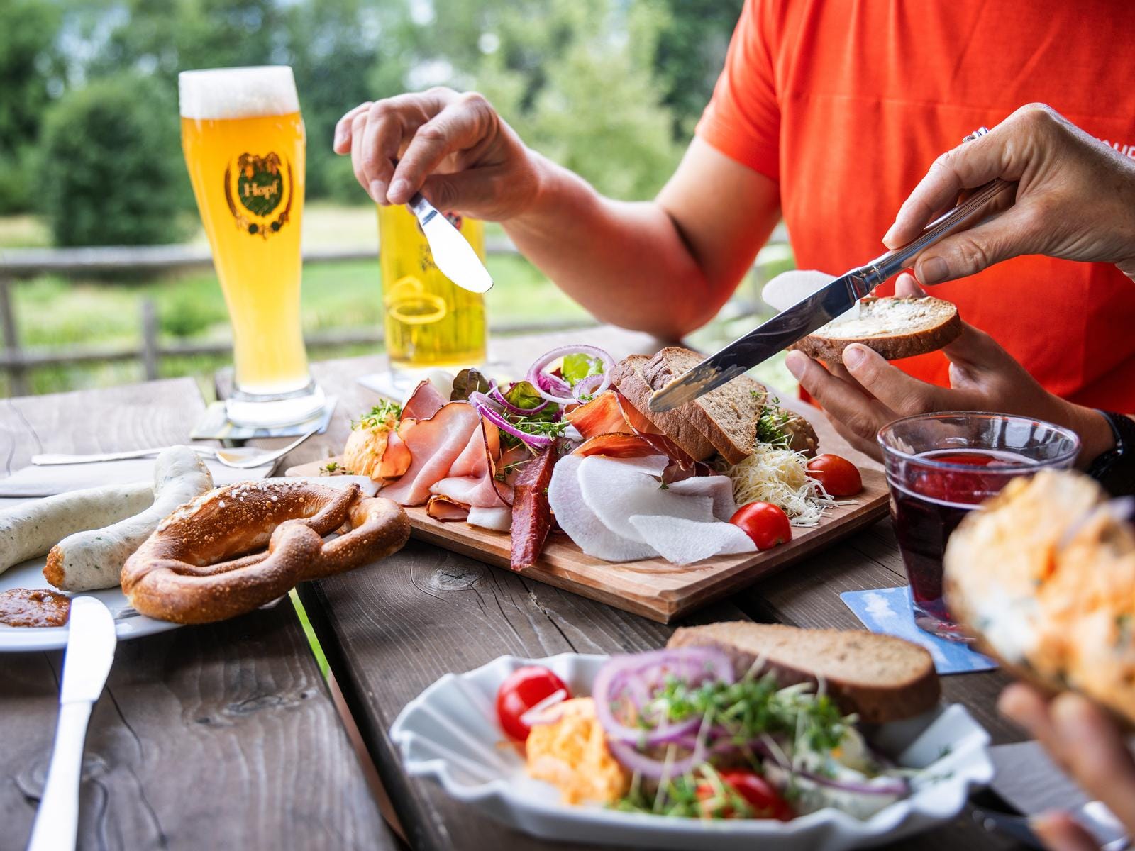 Gemütliche Brotzeit mit Brezn, Obazda und Weißbier im Freien genießen.