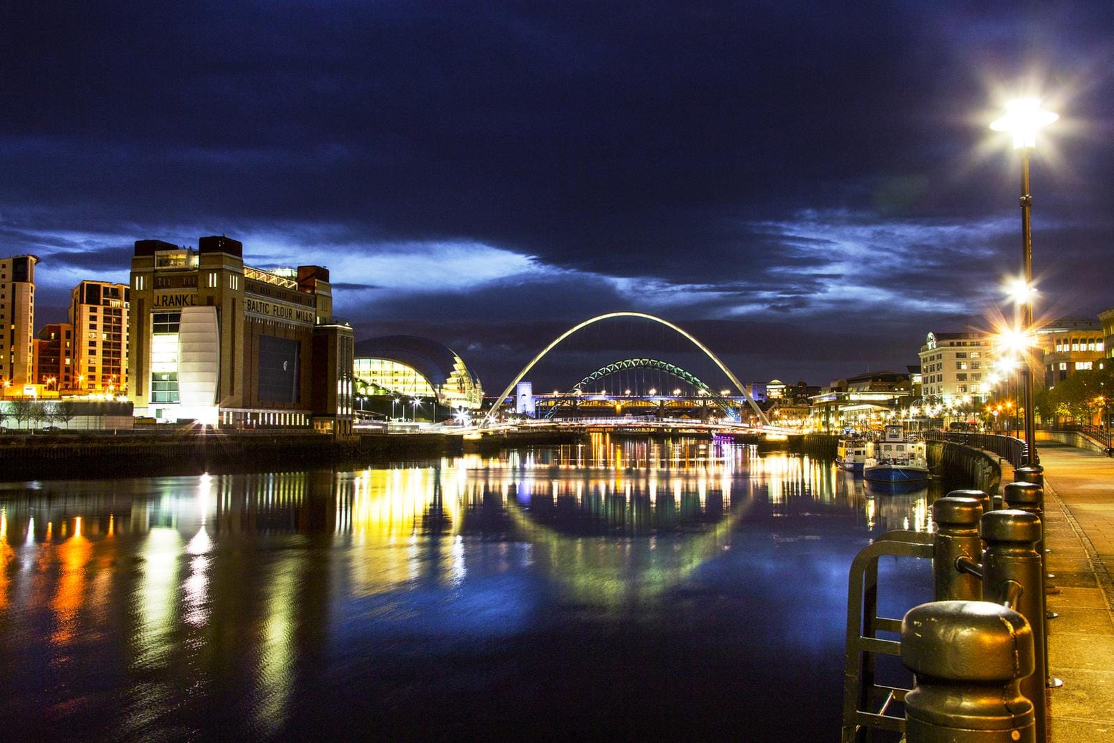Ufer bei Nacht in Newcastle, England mit Millennium Bridge und strahlenden Lichtern.