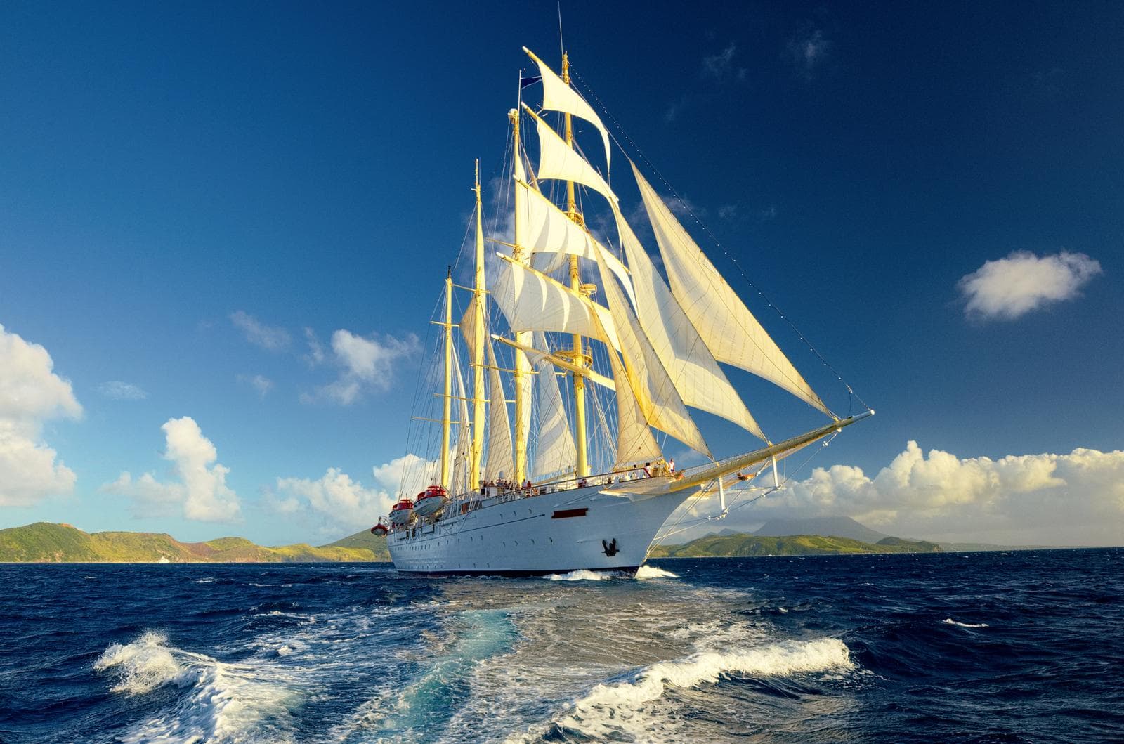 Segelschiff auf offenem Meer bei Sonnenschein, umgeben von Inseln und Wellen.