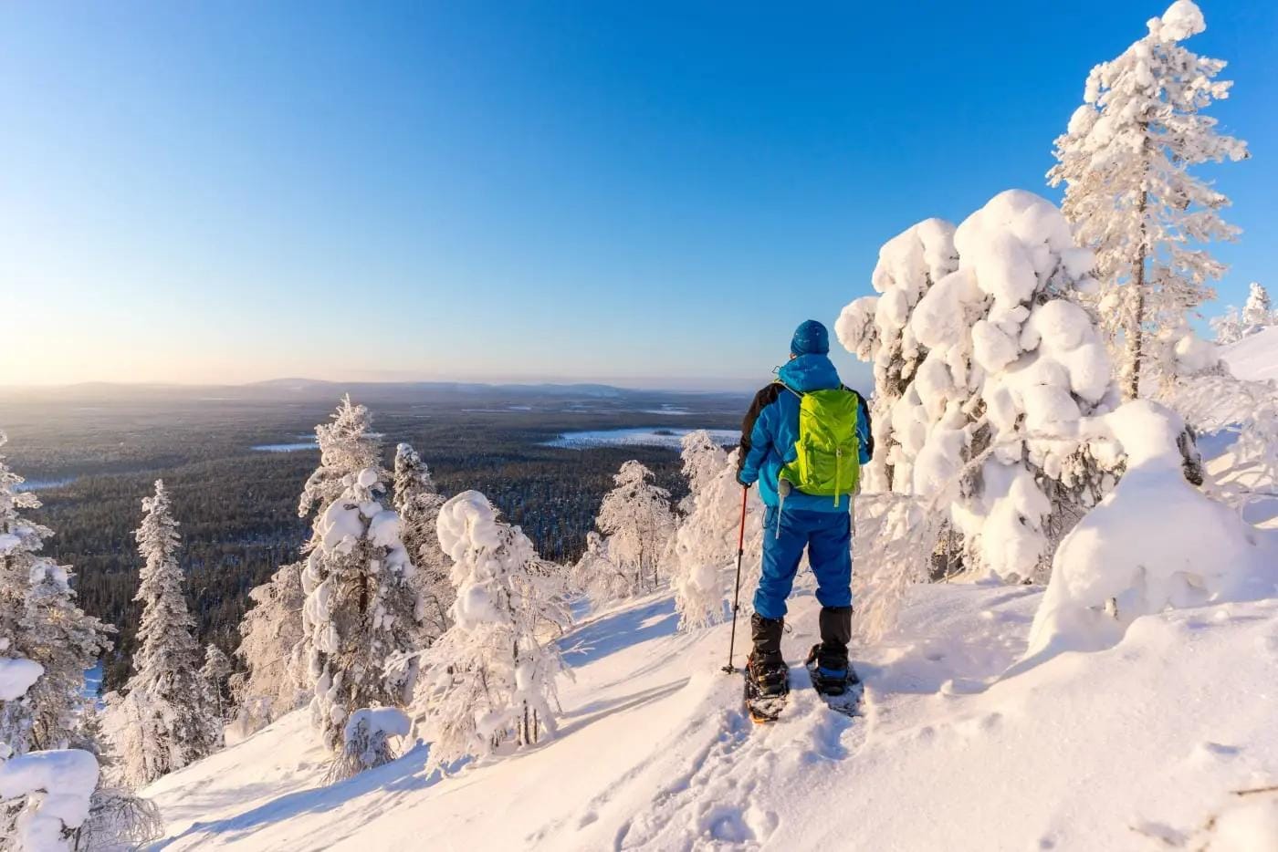 Winterlandschaft in Lappland: Schneeschuhwanderer im Tiefschnee mit Aussicht auf WĂ€lder.