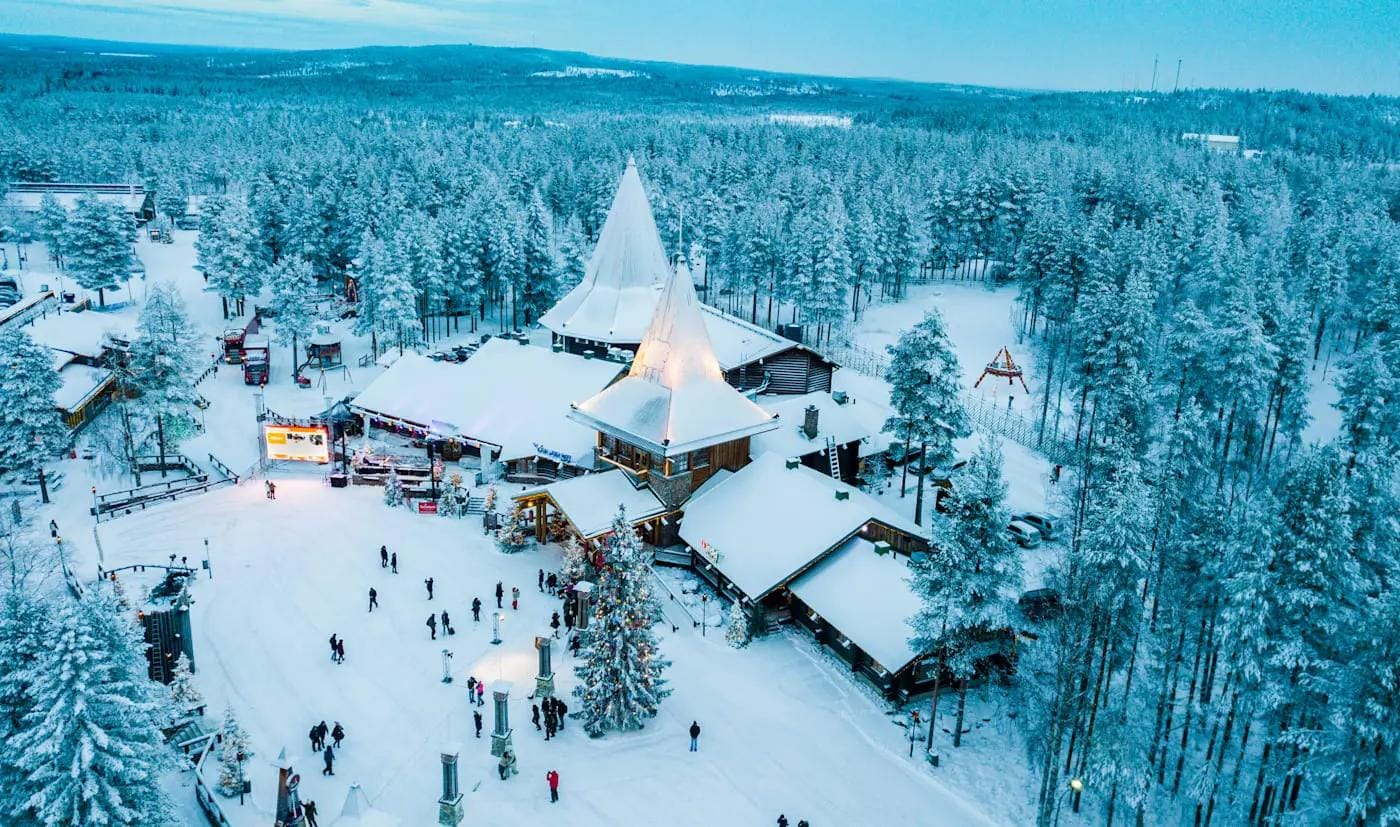 Verschneites Weihnachtsdorf in Lappland mit Tannen und Holzhäusern, winterliche Stimmung.
