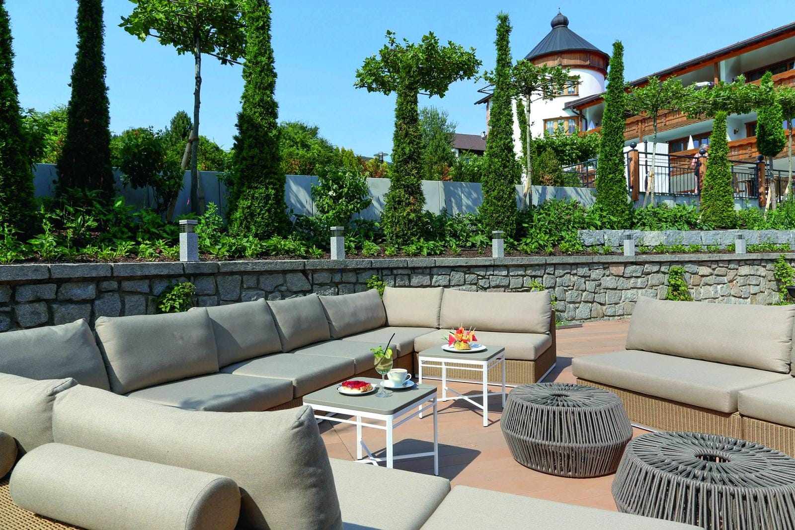 GemĂĽtliche Terrasse in einem Hotel in Deutschland, umgeben von grĂĽner Natur und strahlendem Sonnenschein.