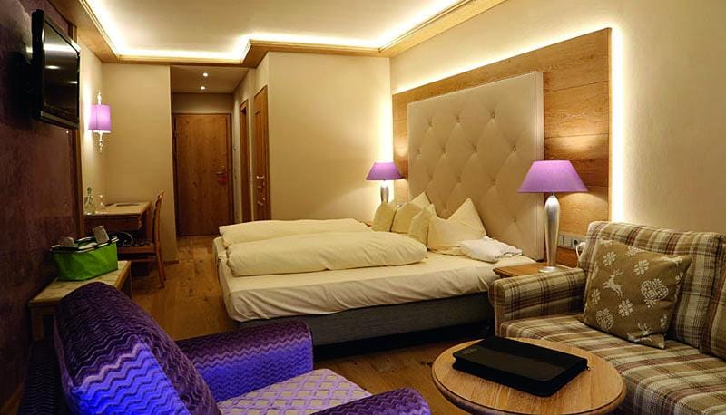 GemĂĽtliches Hotelzimmer in Ă–sterreich mit modernem Design und lila Akzenten fĂĽr Entspannung.