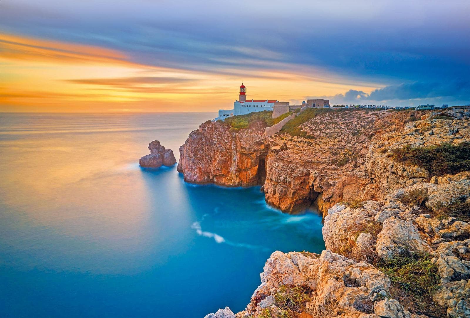 Steilküste mit Leuchtturm am Atlantik bei Sonnenuntergang, Portugal, stimmungsvolle Farben.